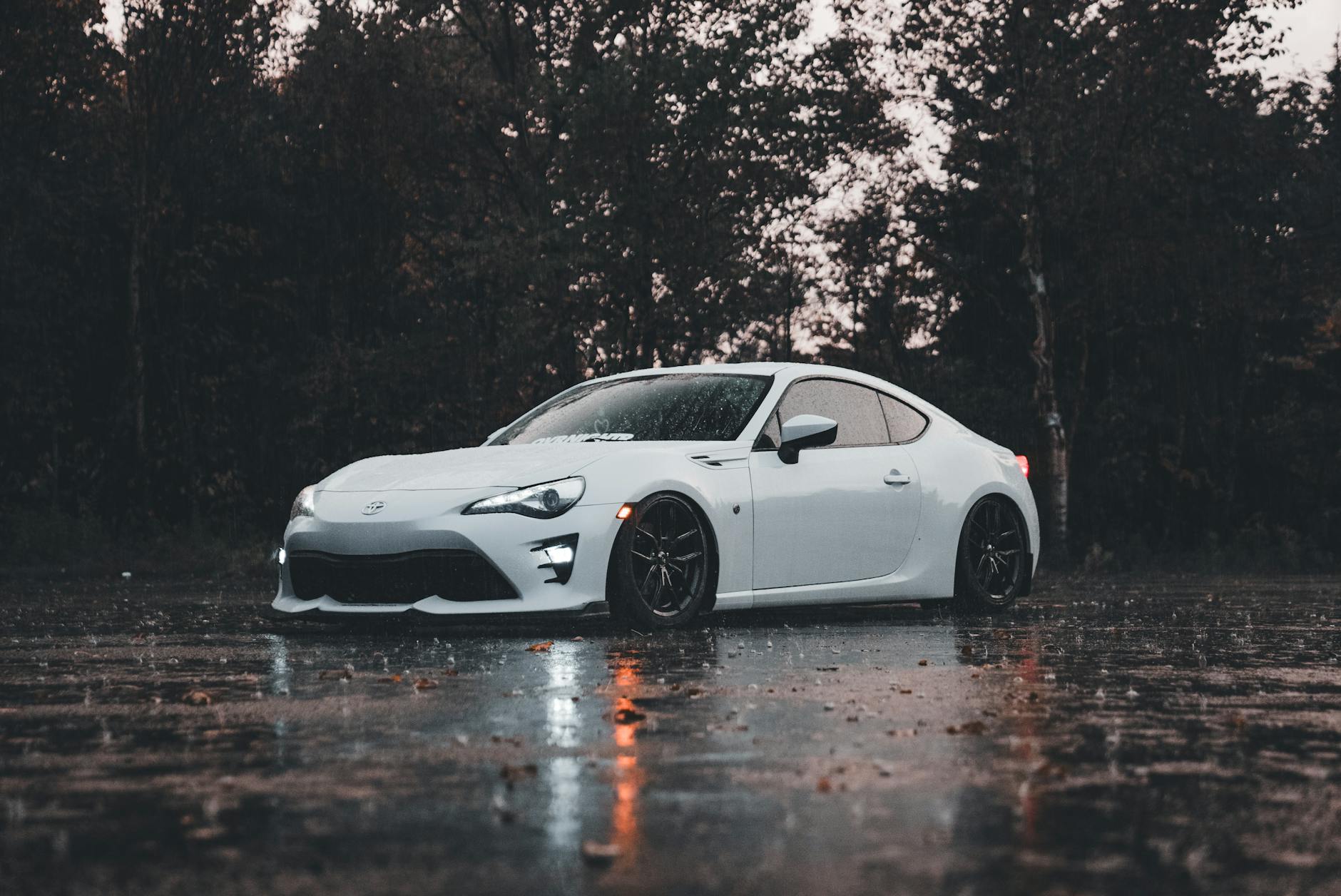 sleek white sports car on rainy road outdoors